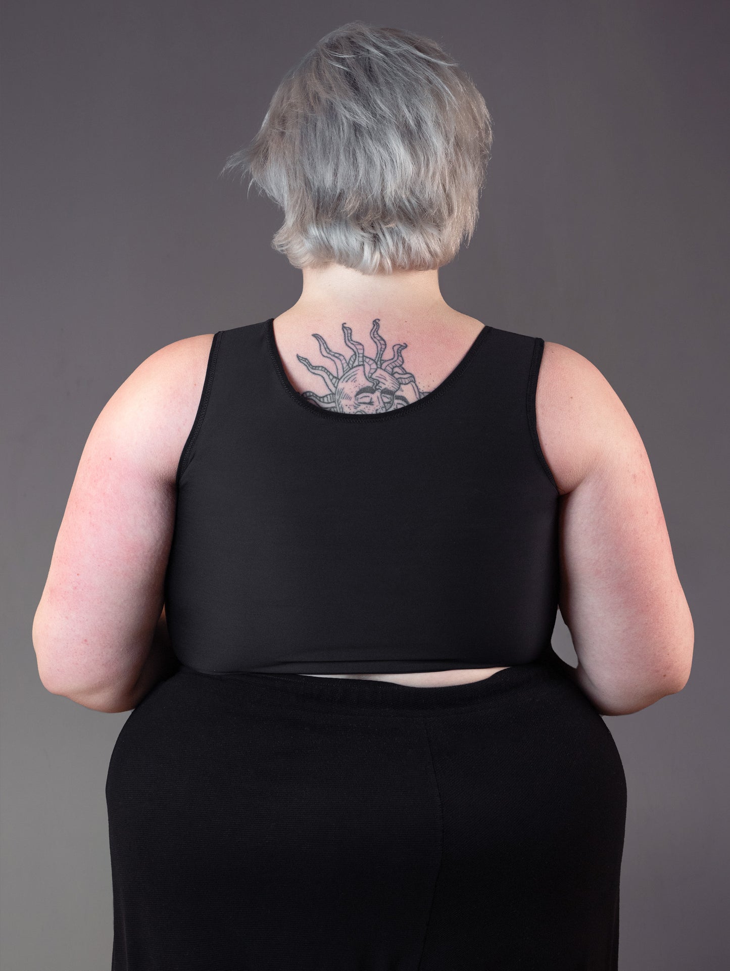 Back view of the UNTAG short binder, modeled by tattooed model Jeannette