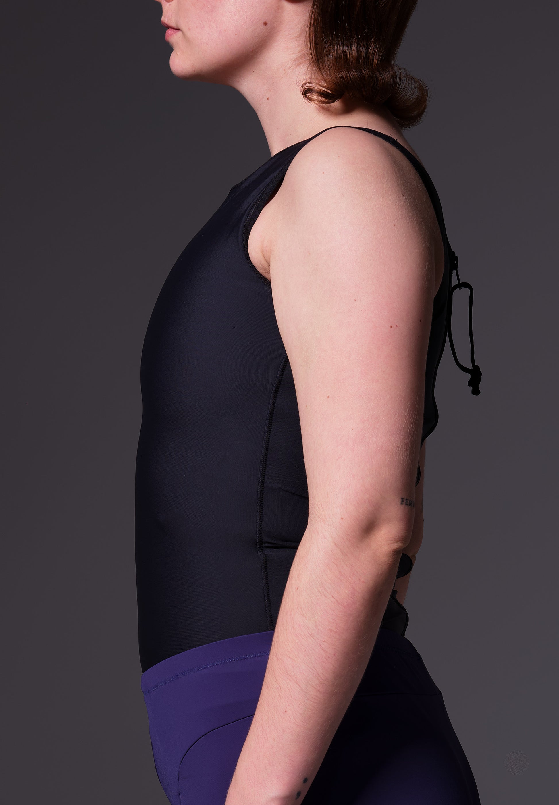 Model Lene is wearing the Swimtop Binder black, seen from the side