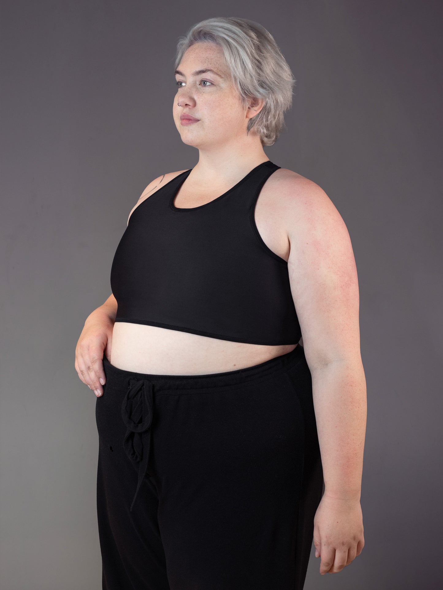 Side view of genderqueer model Jeannette who wears the Tank Binder