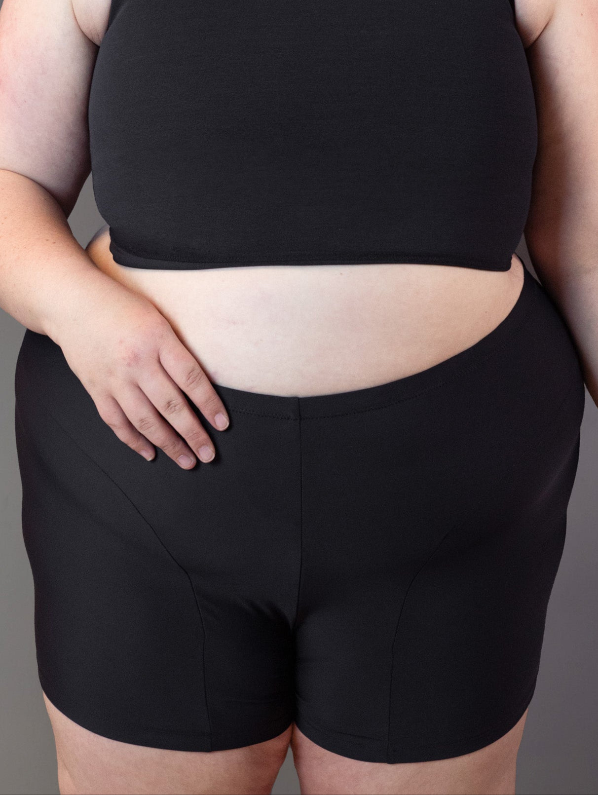 Swim shorts that can be worn with a packer, modelled by plus size genderqueer model.