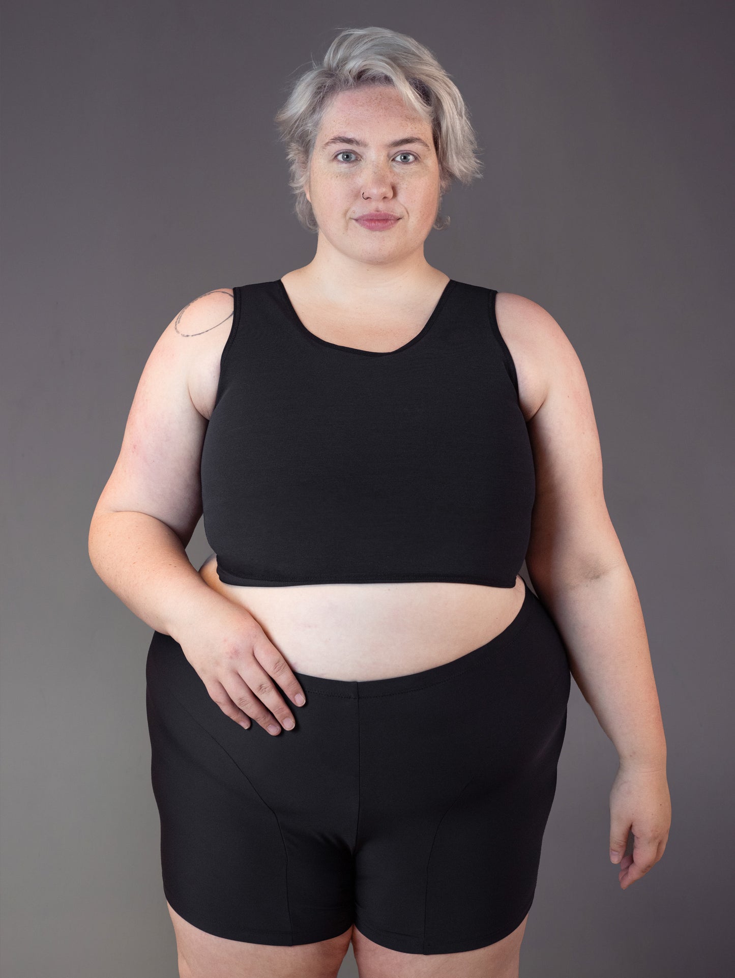 Nonbinary fat model Jeannette wears a black FtM Swim Binder